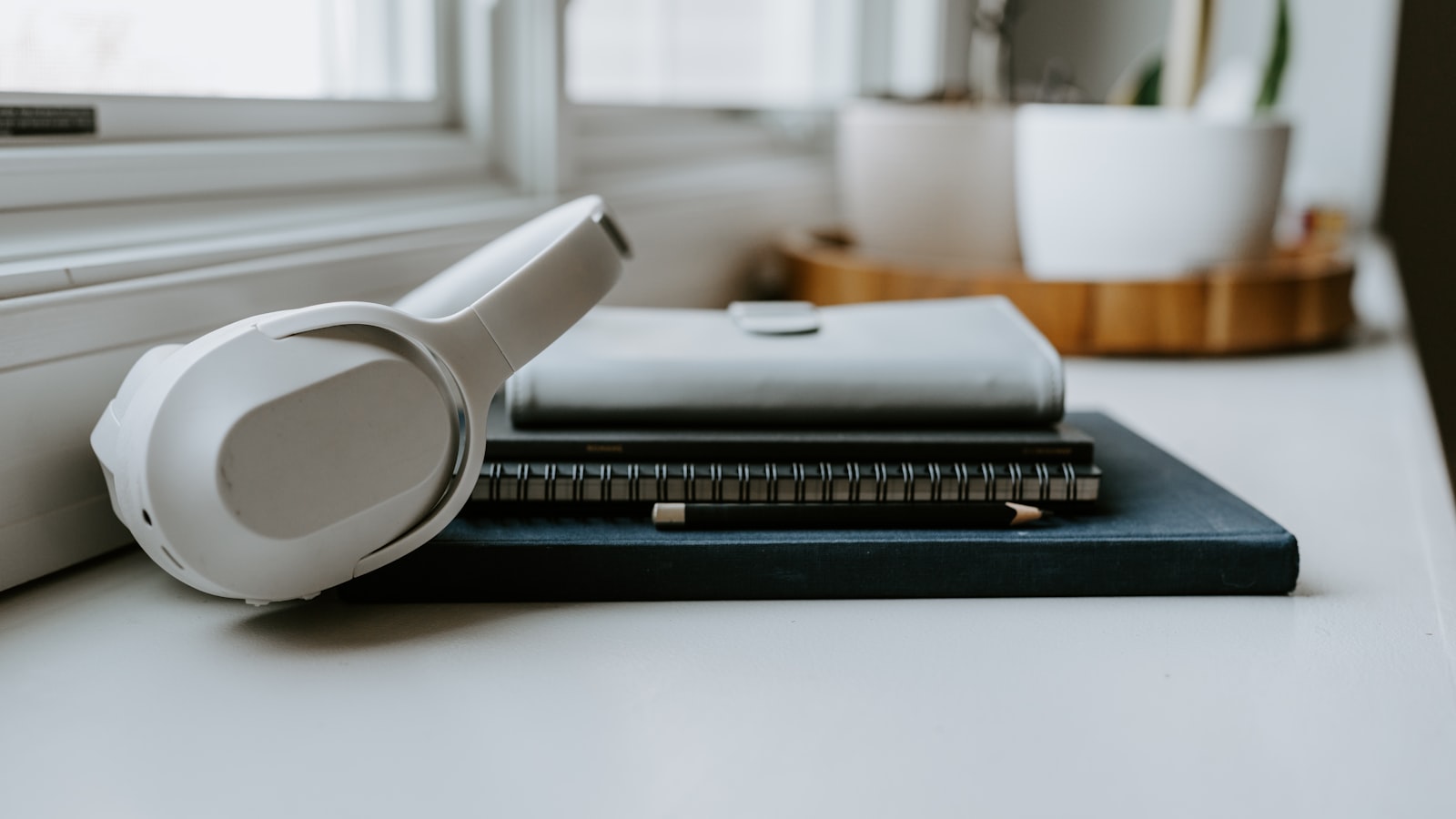 A pair of headphones resting beside an open book in a calm, warmly lit reading corner